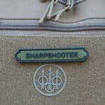 Sharpshooter Velcromerkki Vihreämusta, pitkulaisen muotoinen tarranauhamerkki, mustalla tekstillä "SHARPSHOOTER".